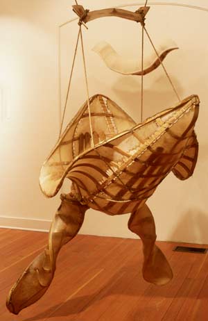 Image of a hanging boat-likesculpture with spiraled arms or 
paddles attached.